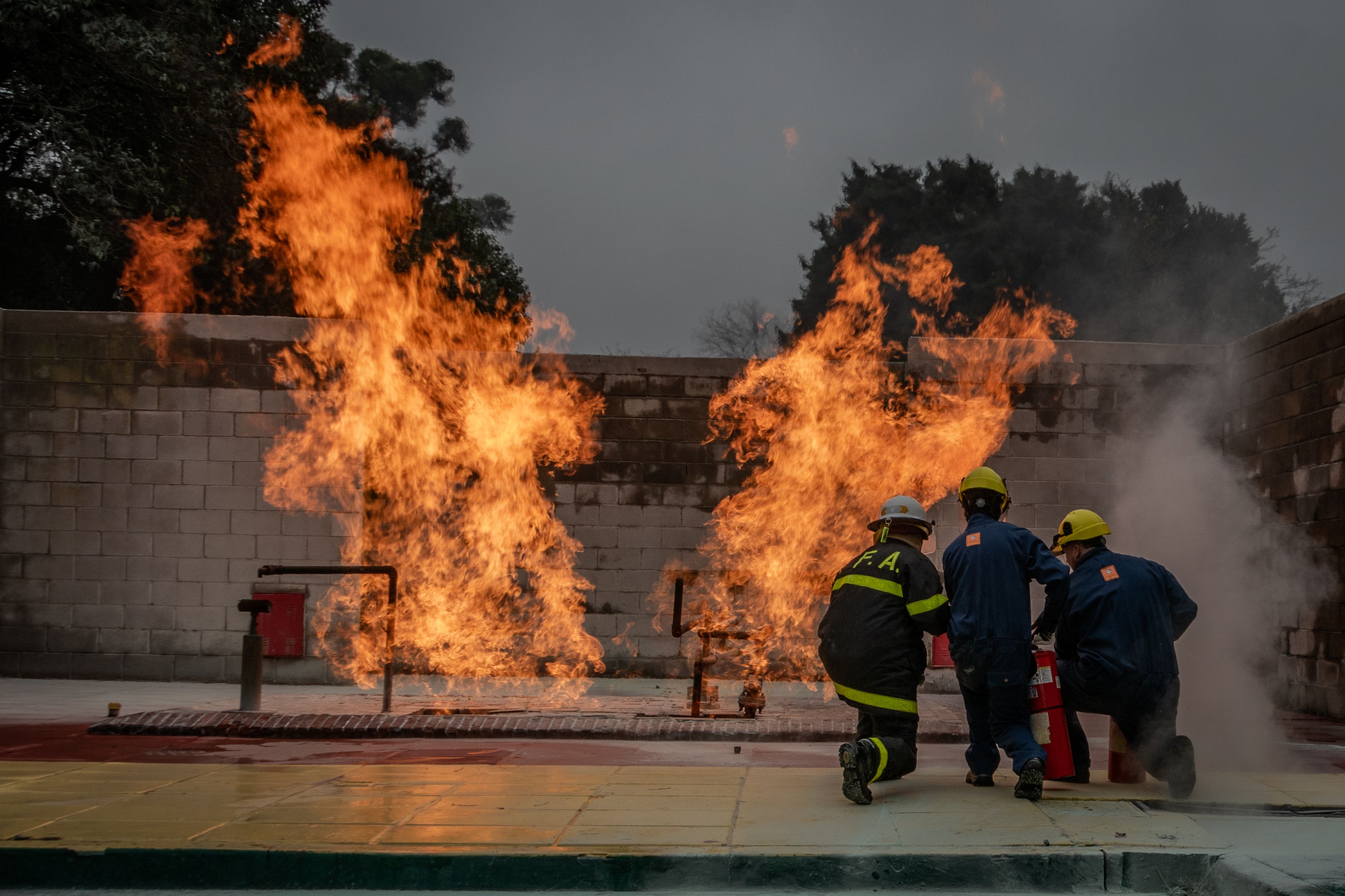 Fire crew in helmets and turnout gear responding to live flames during a suppression drill