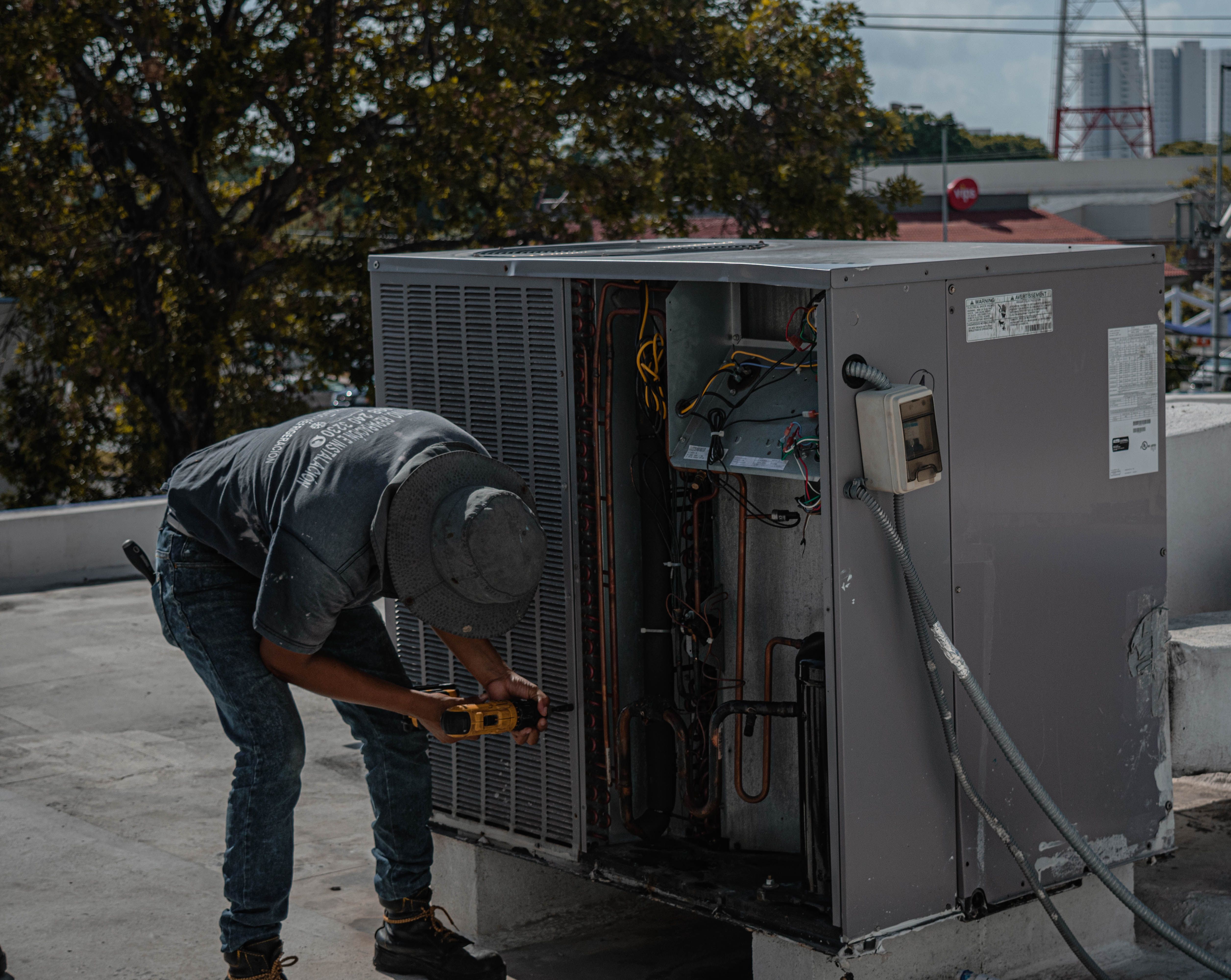 Technician servicing the open condensing unit of a rooftop HVAC system