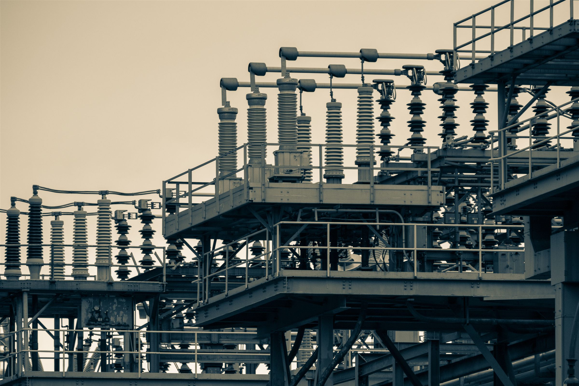 High-voltage switchgear and insulator stacks at a power substation, set against open sky